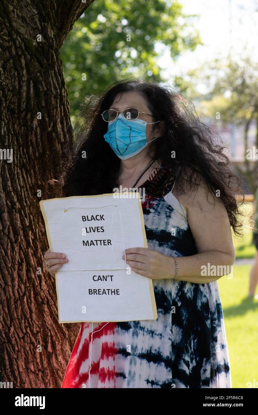 Middle Age White woman wearing a mask and holding a sign at a black lives matter protest Stock Photo