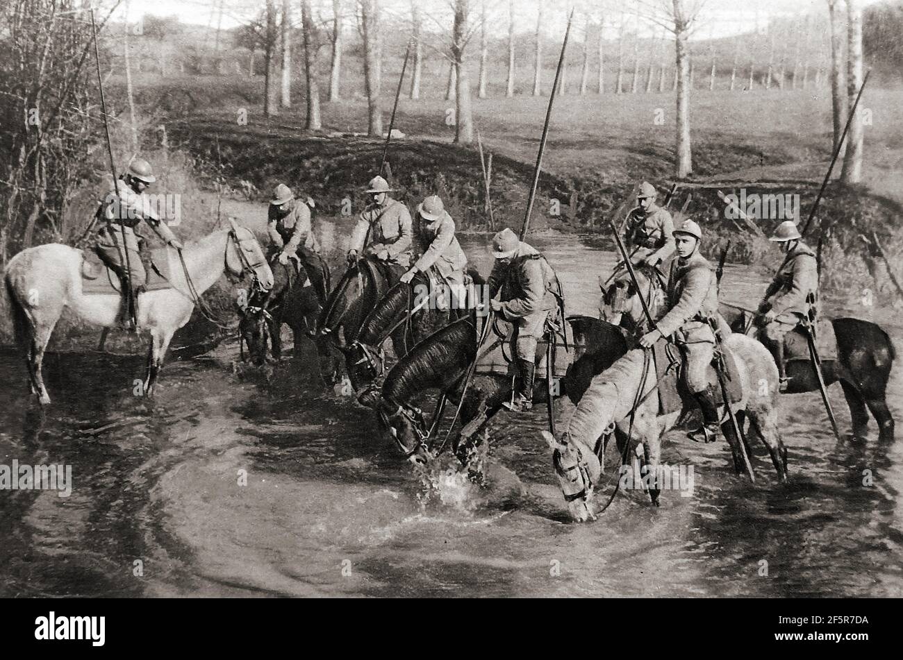 WWI - French Dragoons watering their horses near the front. They were considered one of the finest cavalry units of the time. Dragoons originally were a class of mounted infantry, who   dismounted  from their horses to fight on foot. From the early 17th century  dragoons were  employed as conventional cavalry and trained for combat with swords  or spears and firearms whilst still on horseback. The name dragoon  is derived from a type of firearm, called a dragon, which was a handgun version of a blunderbuss.The modern French Army retains three dragoon regiments of  the original  32 of WWI Stock Photo