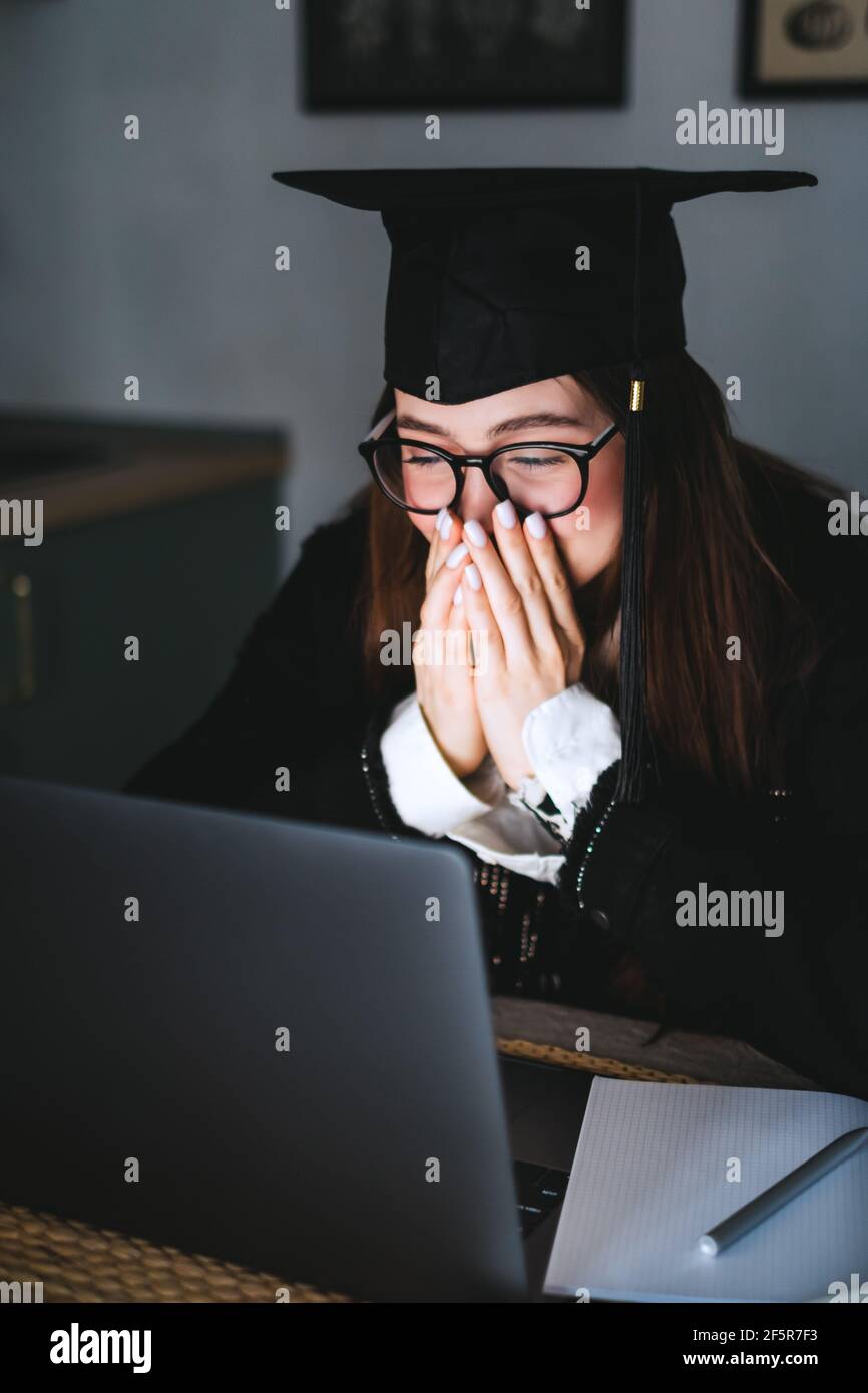 Happy young caucasian woman celebrating college graduation during a video call with friend or family. Stock Photo