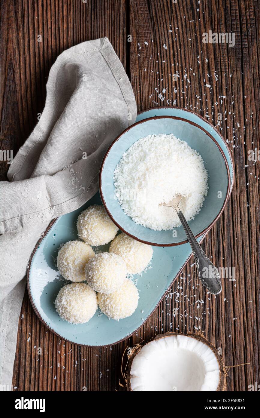 Delicious no bake candy, white chocolate truffles covered in shredded coconut on rustic wooden background Stock Photo