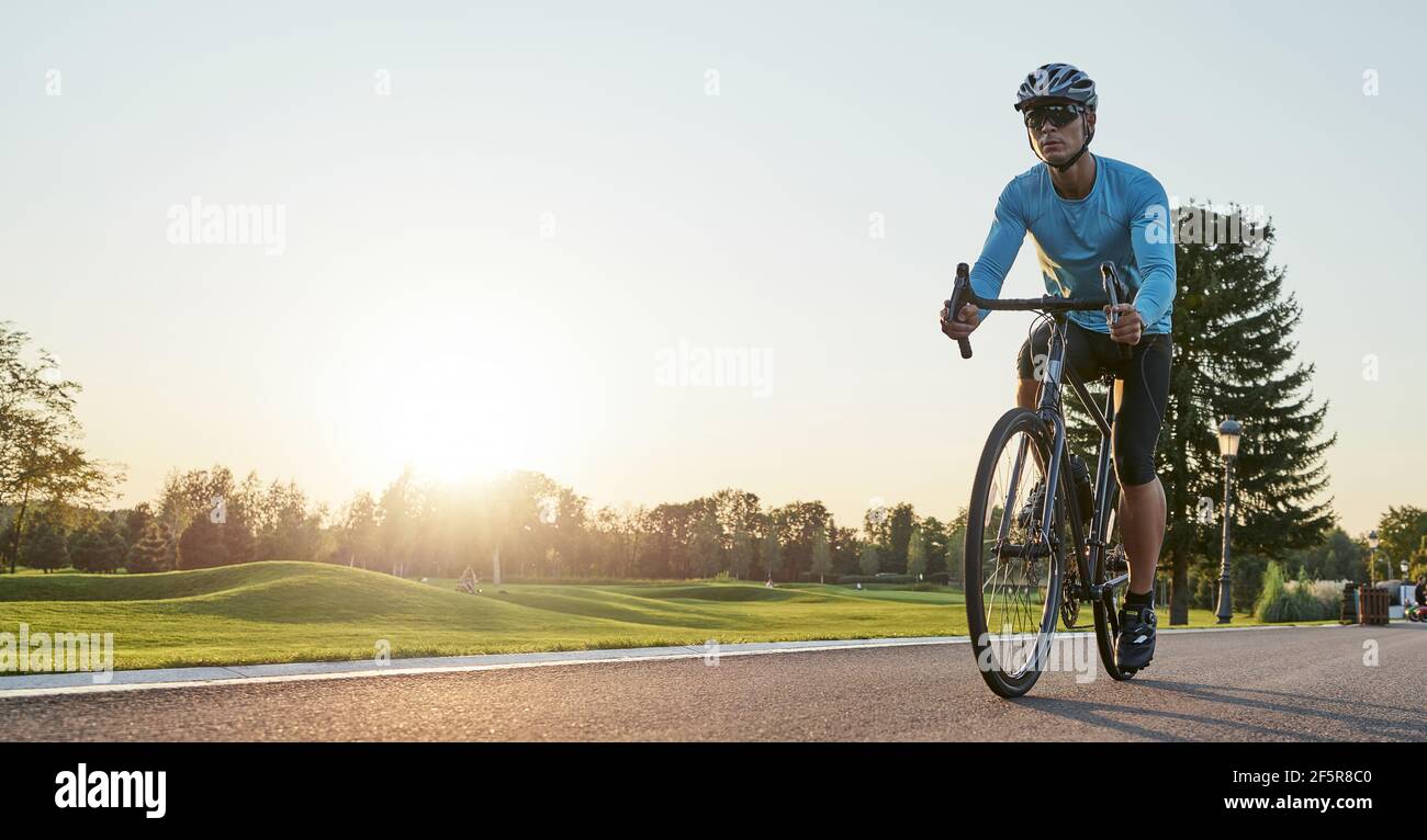 Website header of Rear view of athletic man in sportswear standing with bicycle on the road