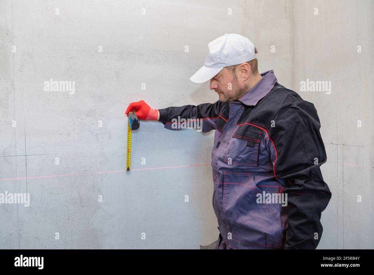 A man, an electrician marks out with a pencil, tape measure and a