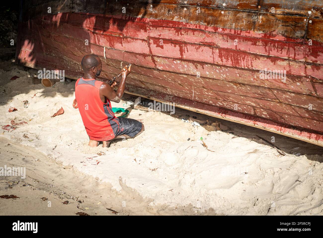 African fisherman on beach repairing his boat Stock Photo