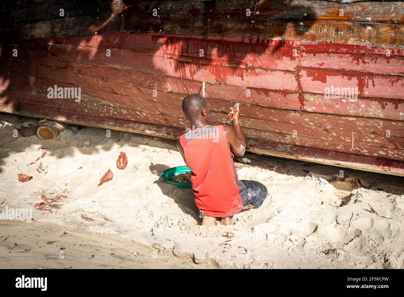 African fisherman on beach repairing his boat Stock Photo