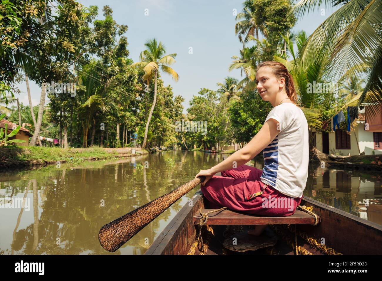 Tourist relaxing on Alleppey backwaters and enjoying beautiful view landscape. Woman sitting on the boat at meditation pose. Kerala, India Stock Photo