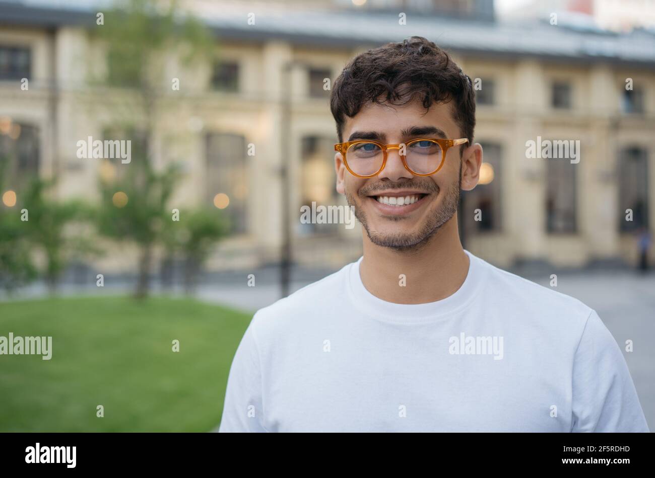 Authentic portrait of young successful Indian man wearing stylish eyeglasses, standing on the street. Handsome asian model looking at camera Stock Photo