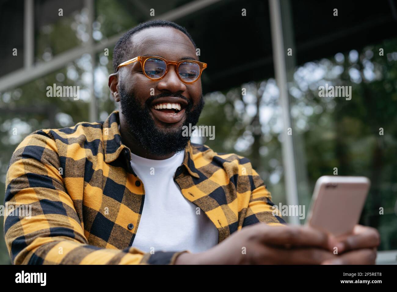 African man using mobile phone. Emotional guy holding smartphone, watching video Stock Photo