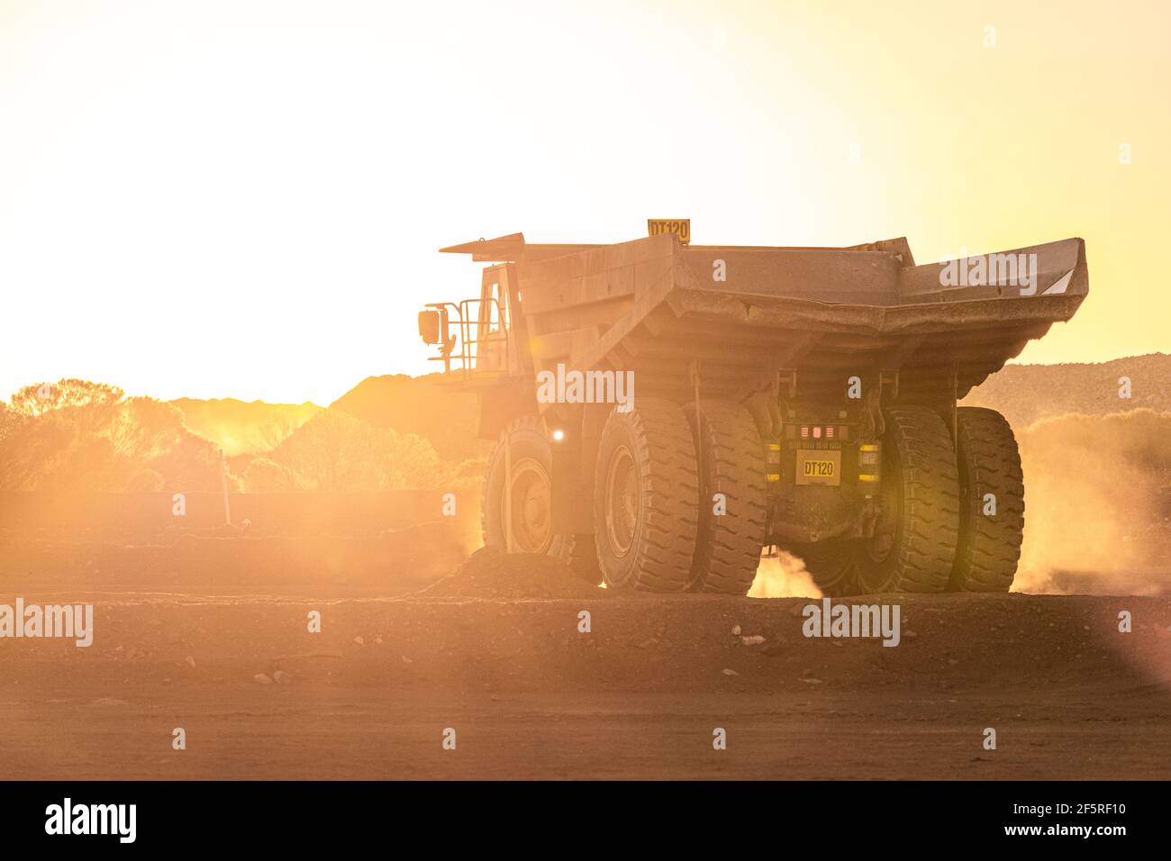 Dump trucks at sunset on mining Go Line in open pit mining area. Stock Photo