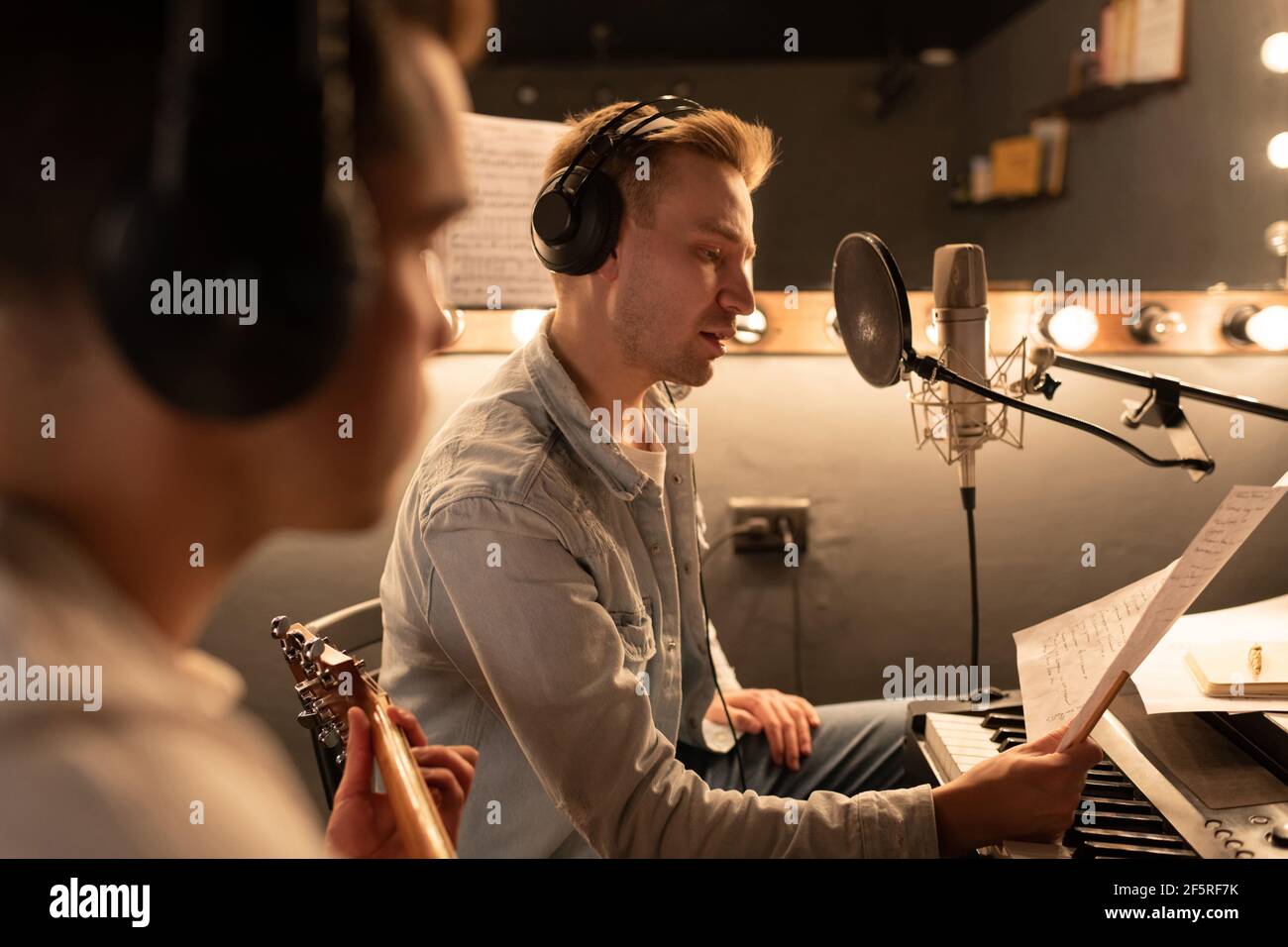 Singer reading song lyrics near guitarist Stock Photo