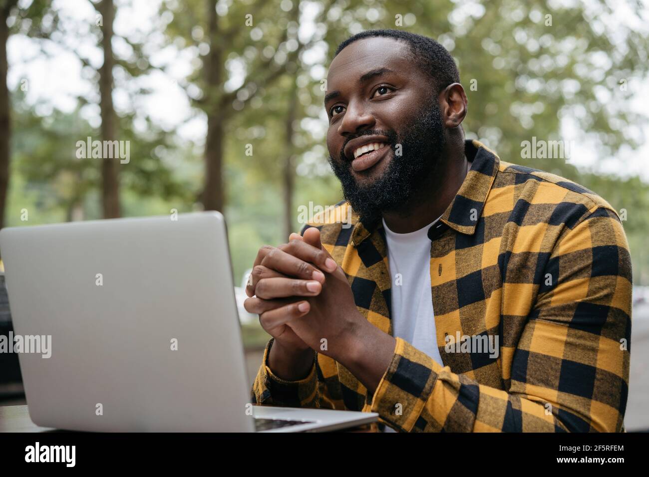Portrait of young African American using laptop computer. Smiling freelancer working, planning project, sitting at workplace Stock Photo