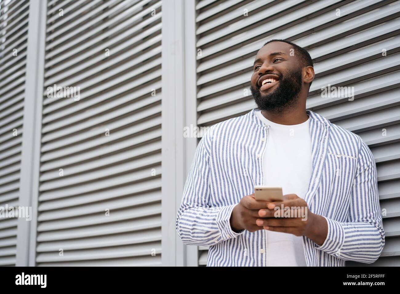 Young smiling African American man using mobile application for online  shopping on black Friday. Portrait of handsome businessman holding  cellphone Stock Photo - Alamy