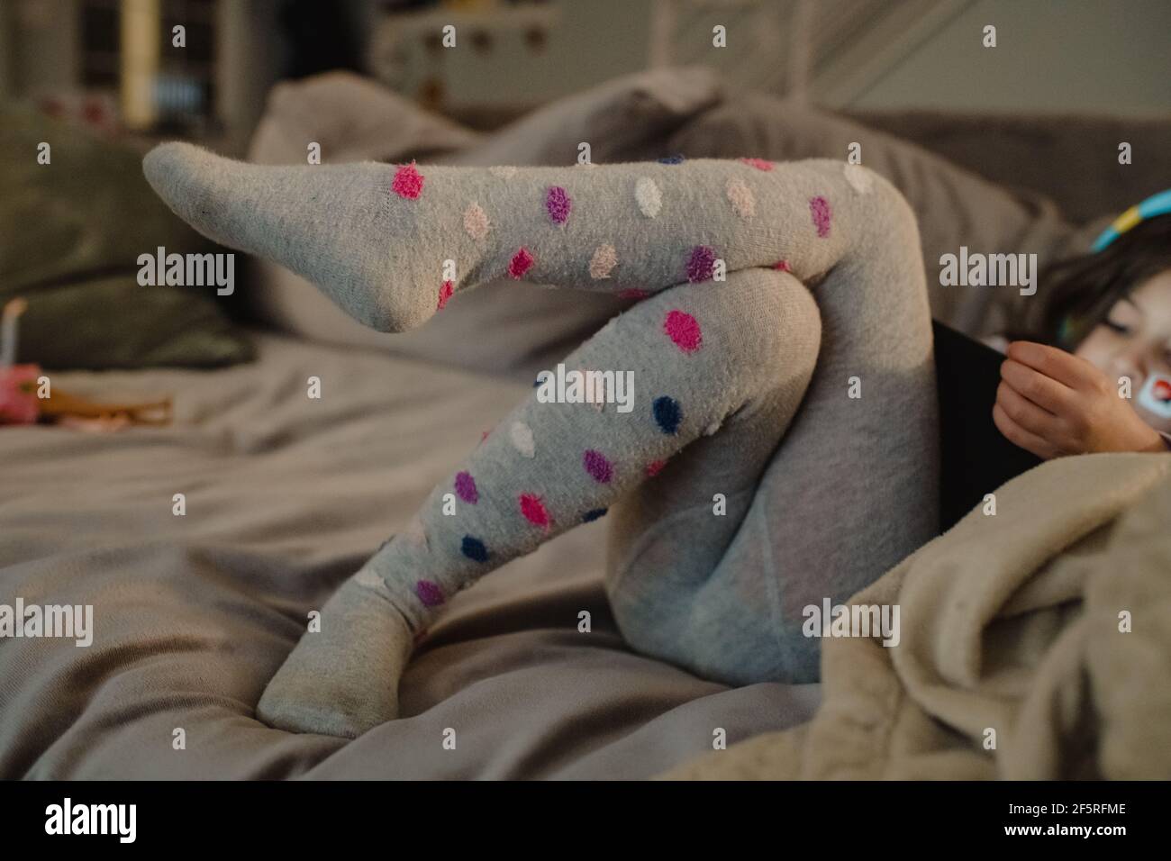 Child playing games on iPad wearing polka dot tights Stock Photo