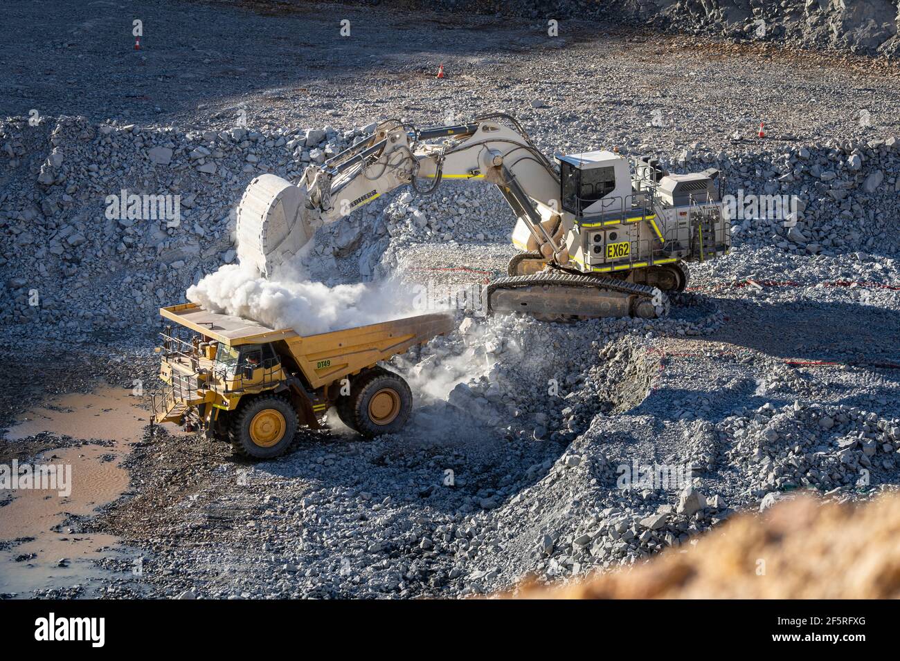 Dusty conditions as digger loads dump truck with ore at gold mine in Western Australia Stock