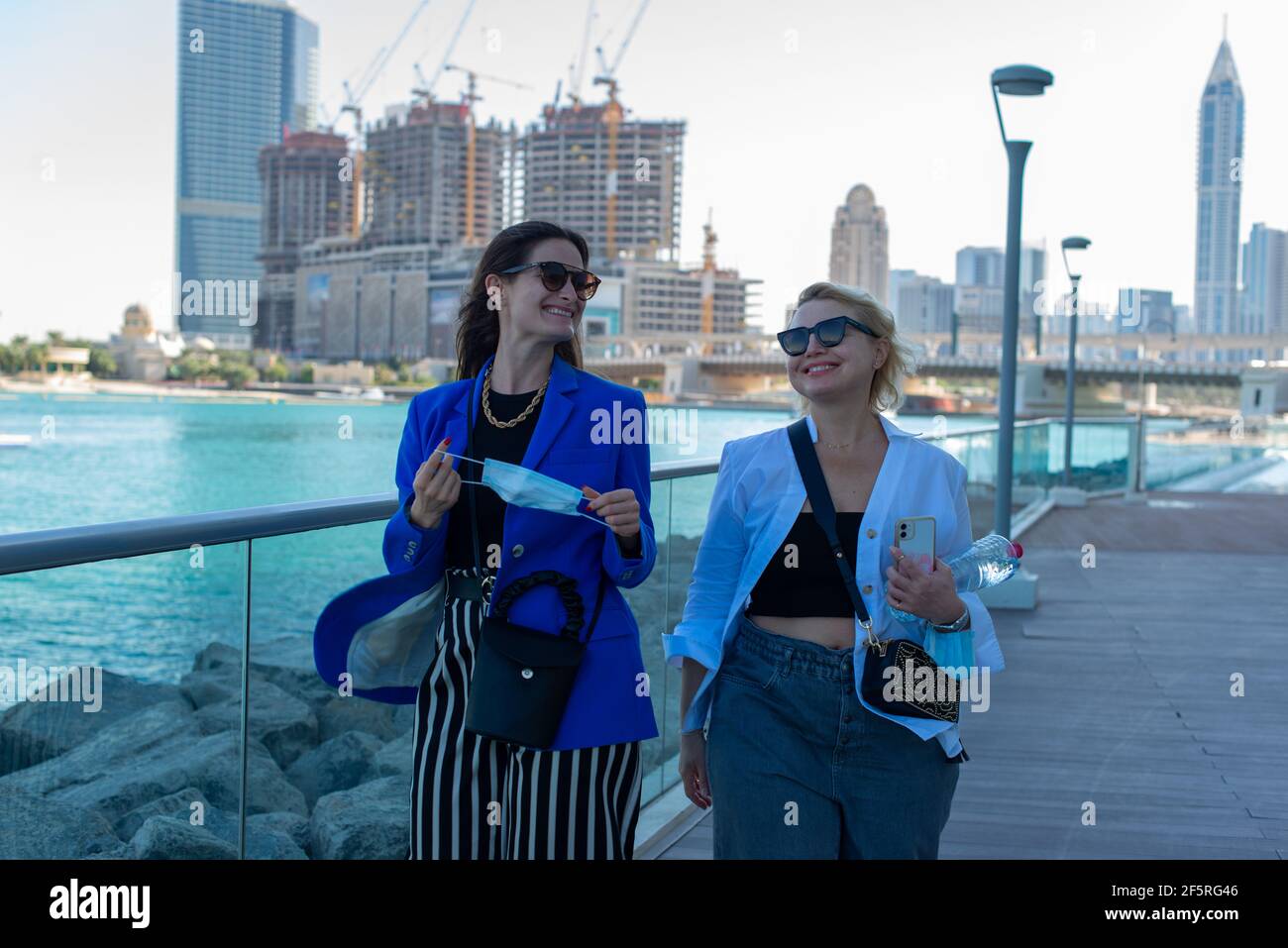 happy women friends walking along seaside smiling and enjoying life Stock Photo