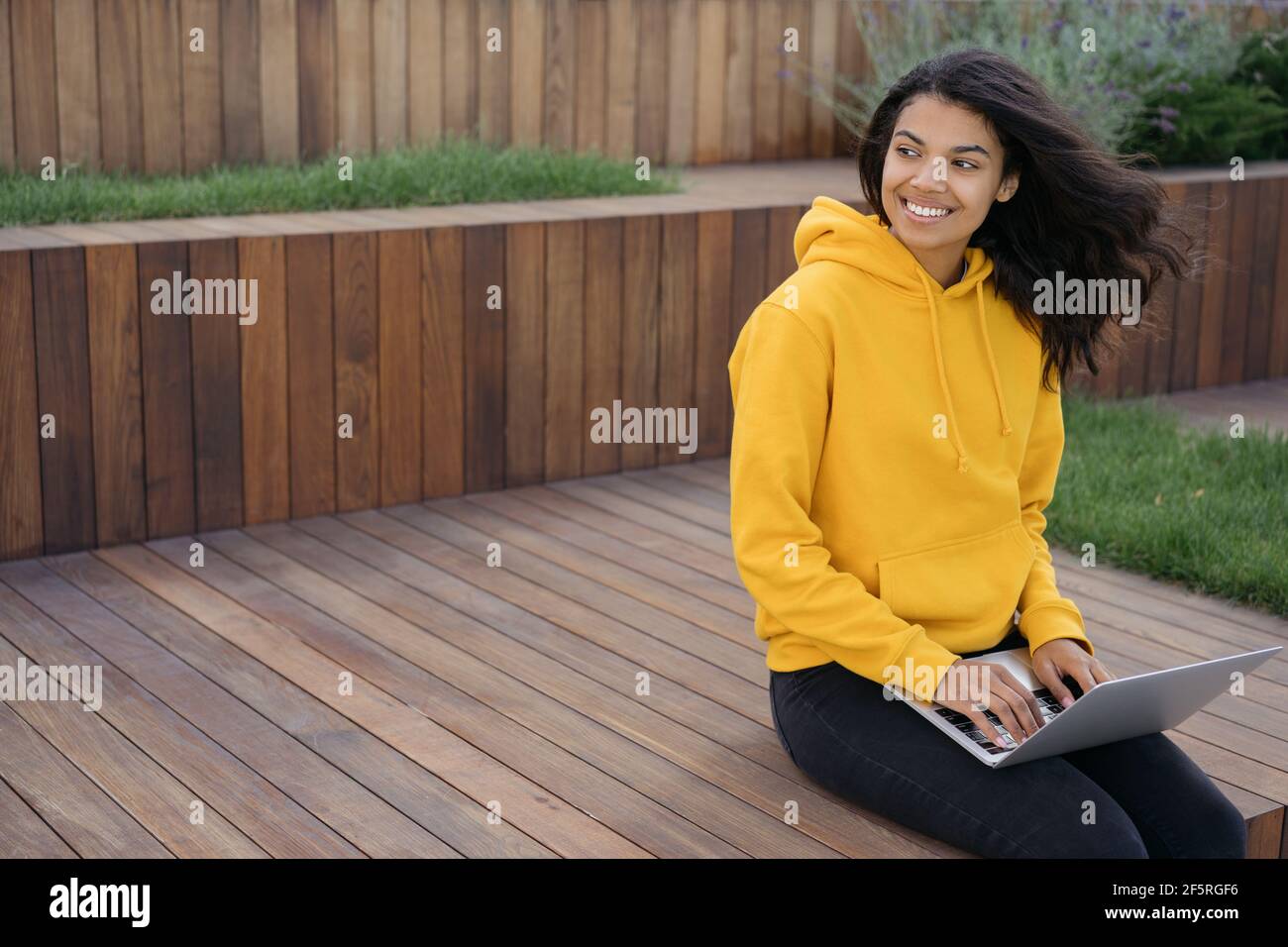 Beautiful African American woman using laptop computer, working freelance project, looking away, copy. Successful student studying, online education Stock Photo