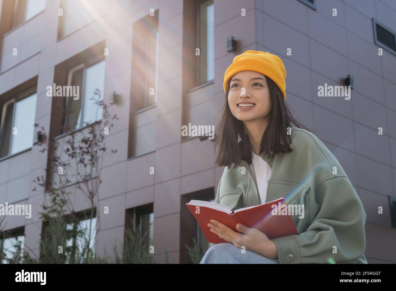 Beautiful smiling asian woman reading book, looking away. Successful university student studying , exam preparation, education concept Stock Photo