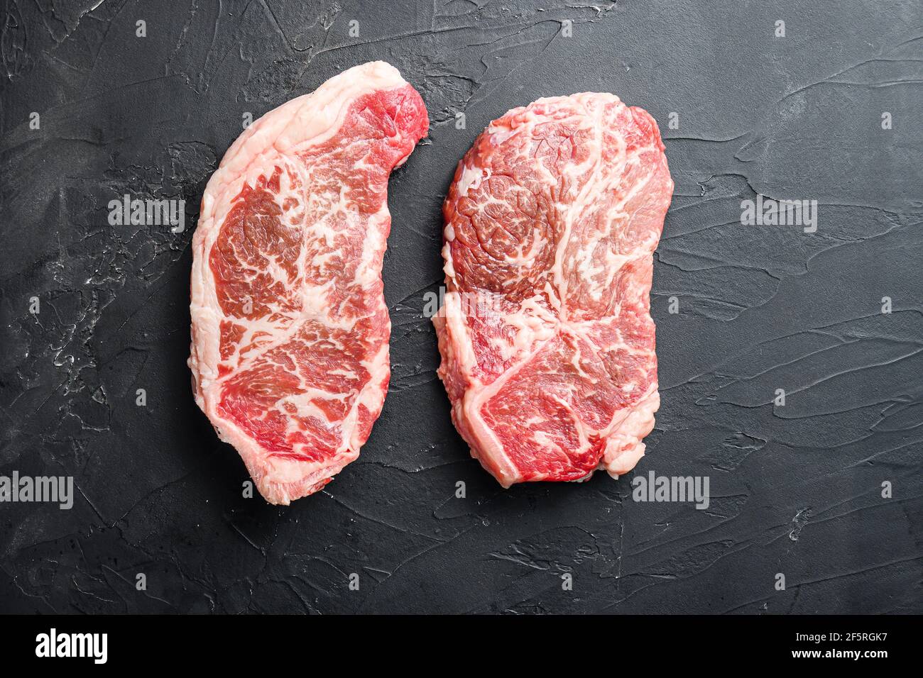 Raw top blade steak cuts, top view on black textured background with ...