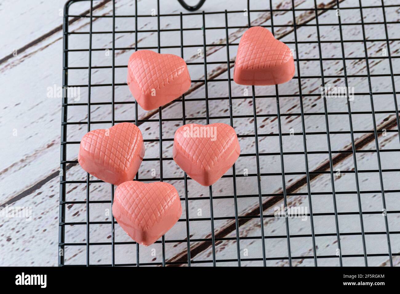 Closeup of several white chocolates tinted with pink paint, on a black railing (with copy space). Stock Photo