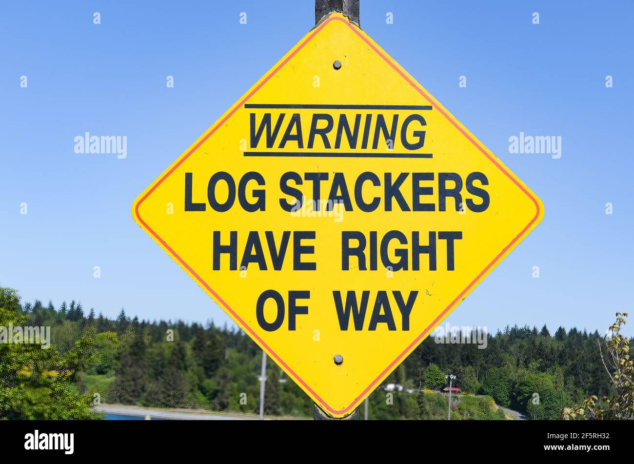 Warning - Log stackers have right of way black on yellow sign in the former logging town of Port Gamble in Washington State Stock Photo