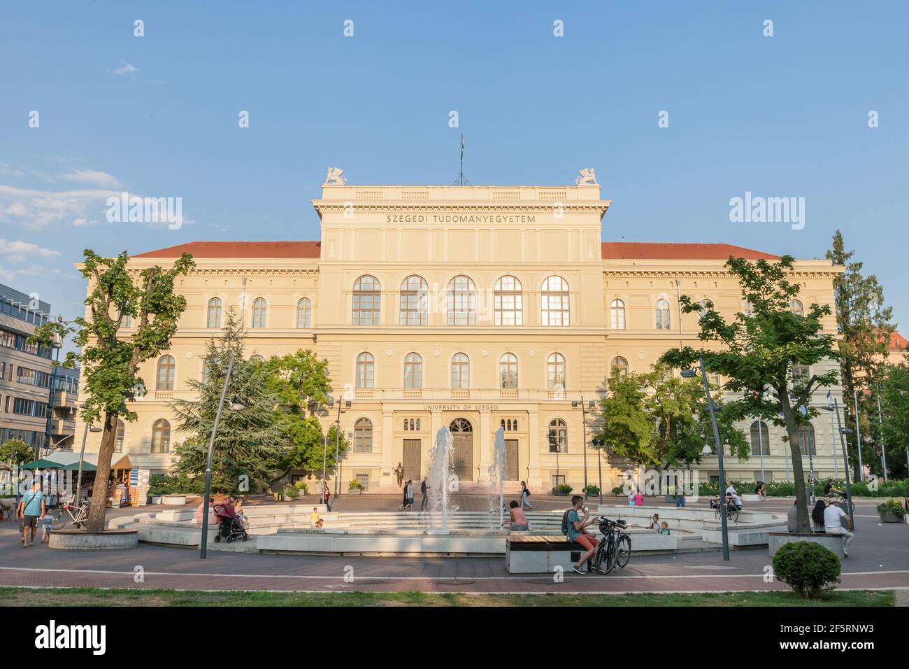 SZEGED, HUNGARY - JULY 20, 2017: Main facade of Szeged University, on the Dugonics Ter Square, with the iconic Fountain with people sitting behind. Th Stock Photo