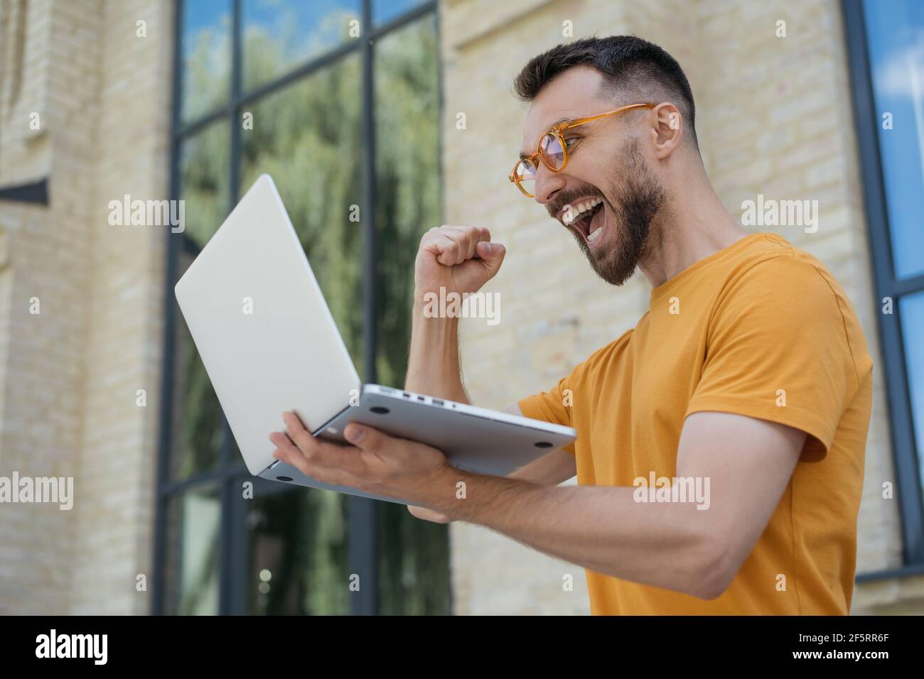Overjoyed online lottery winner looking at digital screen celebration success. Sport betting concept. Excited man using laptop computer Stock Photo
