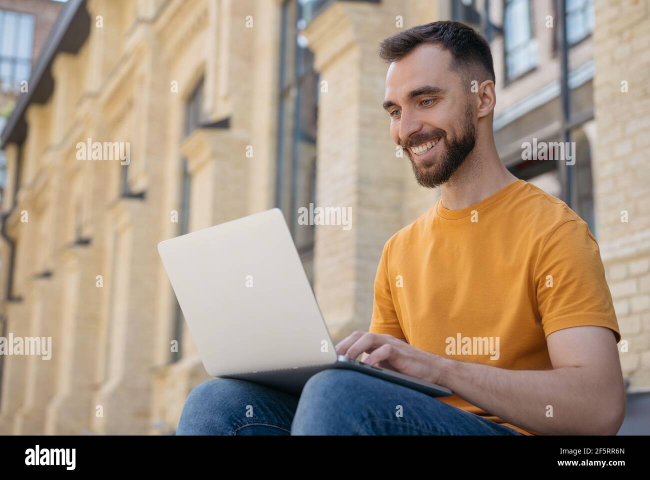 Young handsome programmer using laptop computer. Smiling man copywriter typing, communication, working online Stock Photo