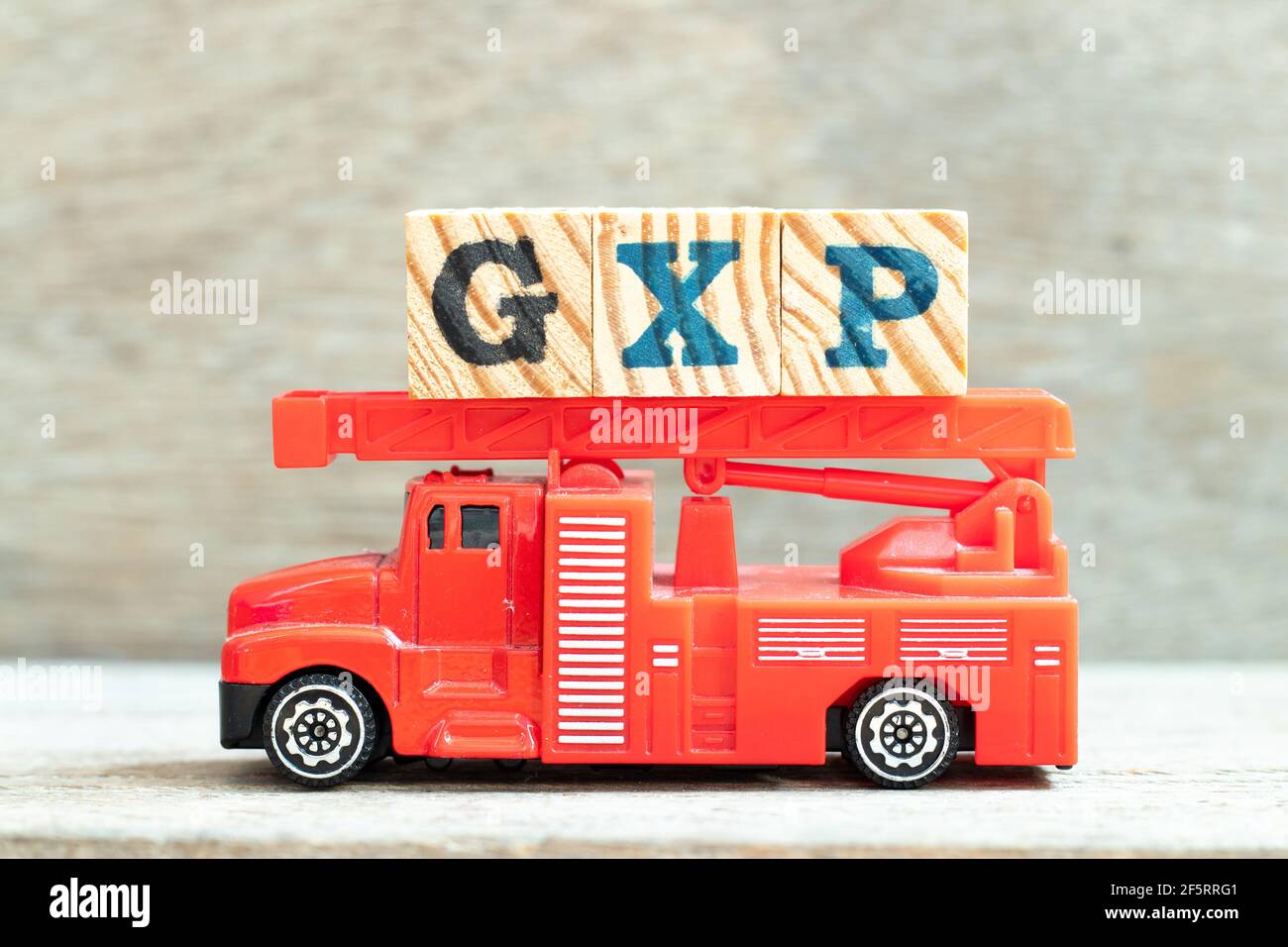 Fire ladder truck hold letter block in word GXP on wood background Stock Photo