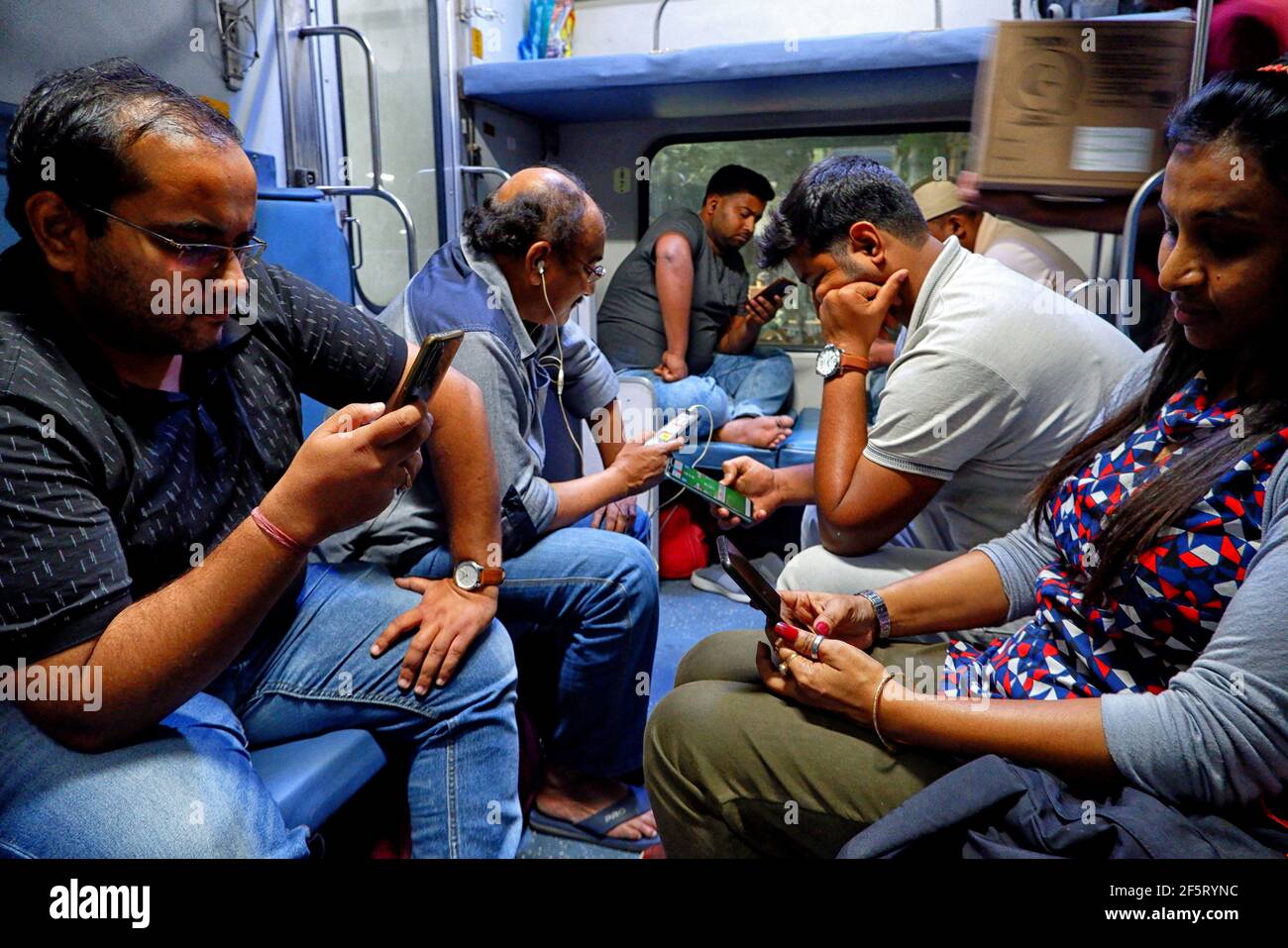 Delhi, India. 21st Mar, 2021. Passengers are seen browsing their Mobile Phones inside a Railway Coach of Rajdhani Express without wearing any protective gears.India has recorded 61187 new Covid 19 cases on March 27, 2021 where the government plans to re inforce lockdown/containment measures from April 2021 onwards to tackle the Second wave of the Covid 19 pandemic. Credit: SOPA Images Limited/Alamy Live News Stock Photo