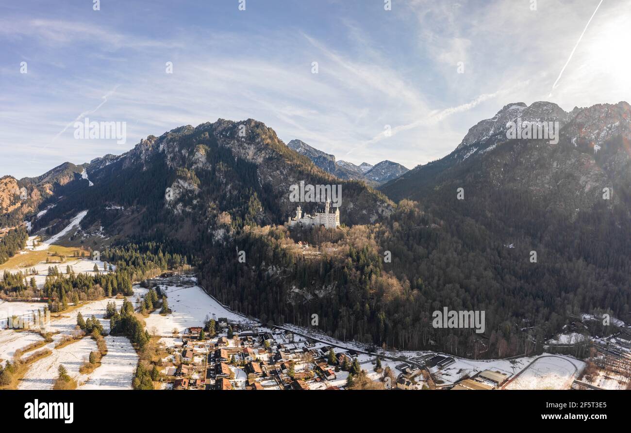 Aerial drone shot of picturesque Neuschwanstein Castle on snowy hill in winter sunlight in Germany Stock Photo