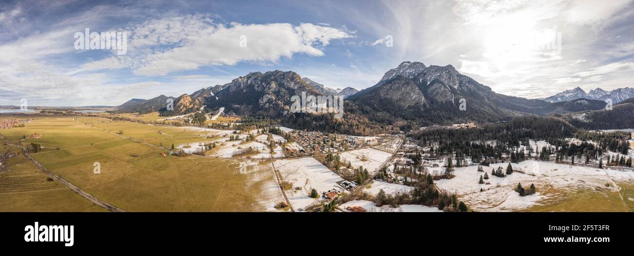 Aerial panorama drone shot of picturesque Neuschwanstein Castle on snowy hill in winter sunlight in Germany Stock Photo