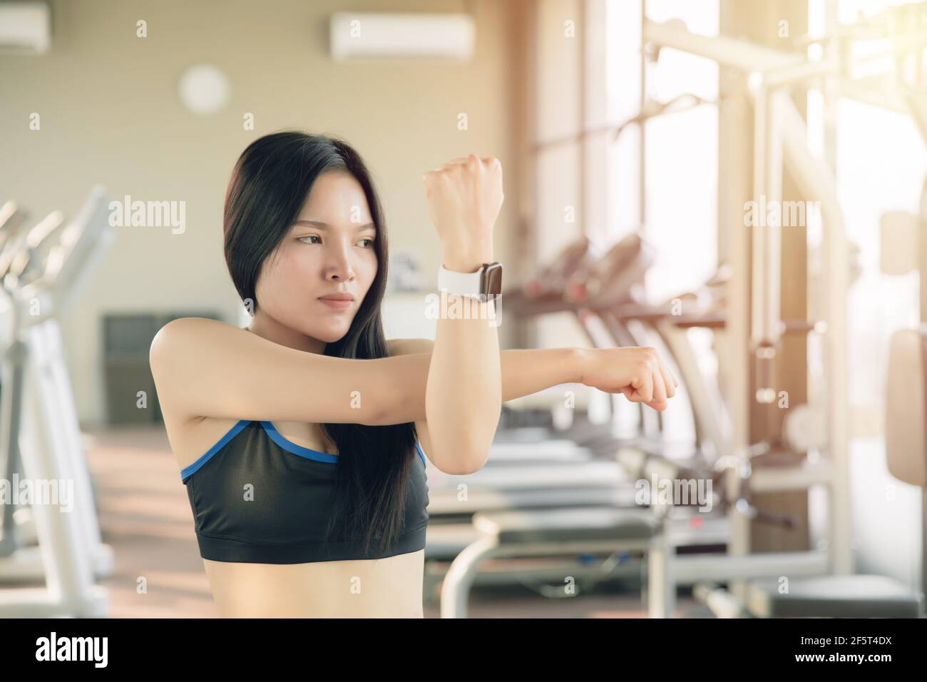 Young Asian healthy woman doing arm muscle stretching, warm up before exercising. Stock Photo