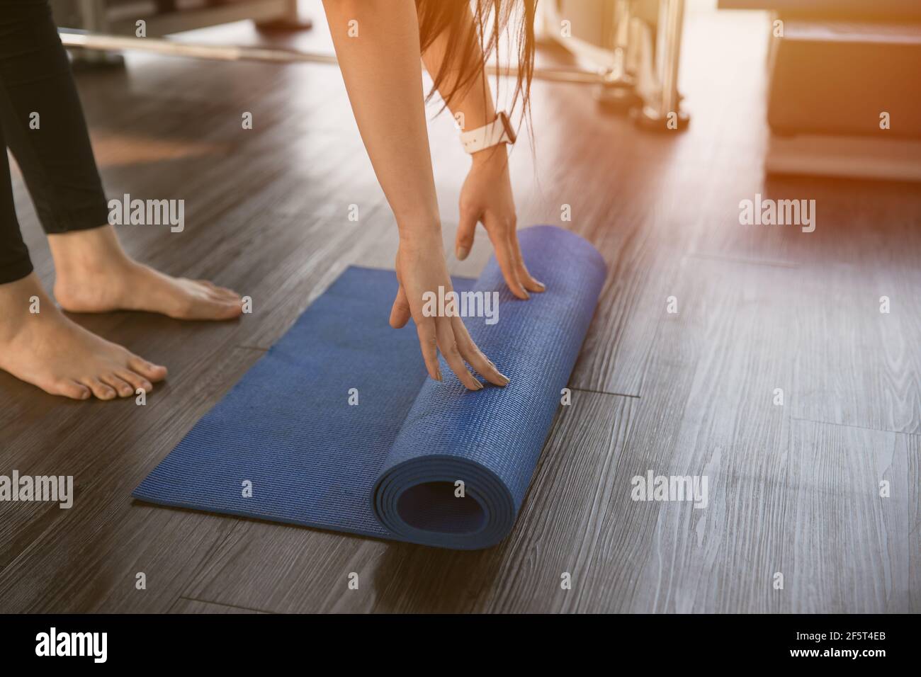 Healthy woman rolling preparing yoga mat for fitness class Stock Photo