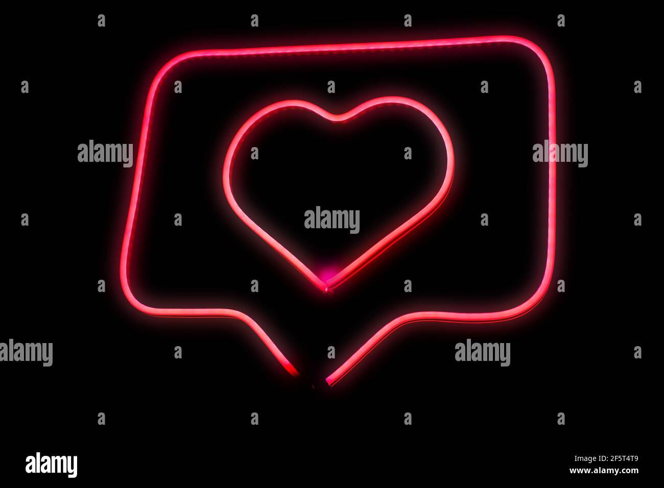 Neon light pink heart love in chat bubble box isolated grow in the dark background. Stock Photo