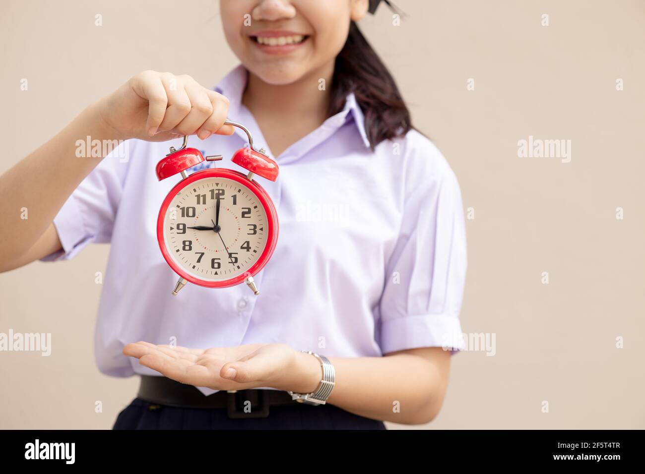 Asian Student handle alarm clock for education times or go to school happy smile. Stock Photo