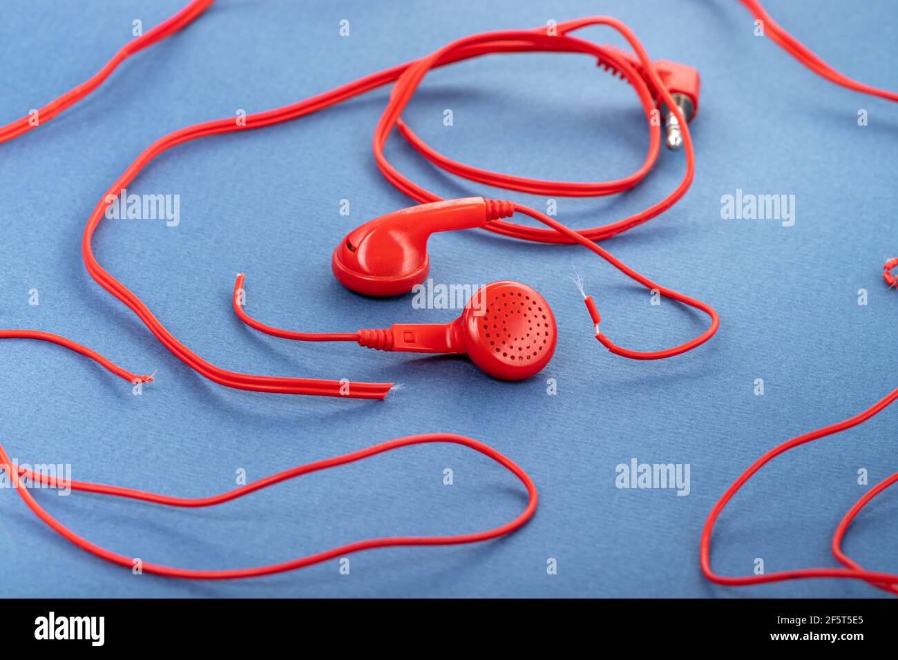 Headphones on a blue background. Torn headphones. Repair of electronic  devices. Broken wire Stock Photo - Alamy