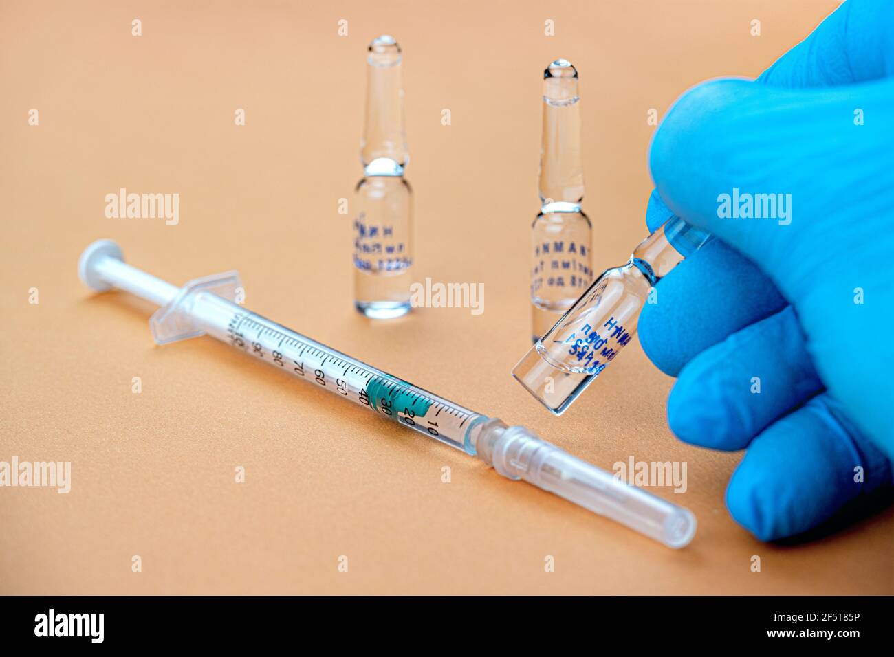 A medic holds a syringe with the Sputnik-V coronavirus vaccine in a protective blue medical glove Stock Photo