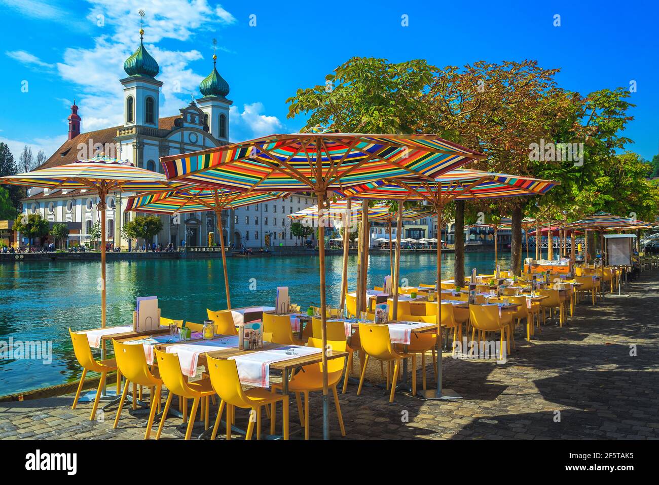 Cozy waterfront street restaurant on the shore of the Reuss river. Street cafe with colorful umbrellas on the walkway, Lucerne, Switzerland, Europe Stock Photo