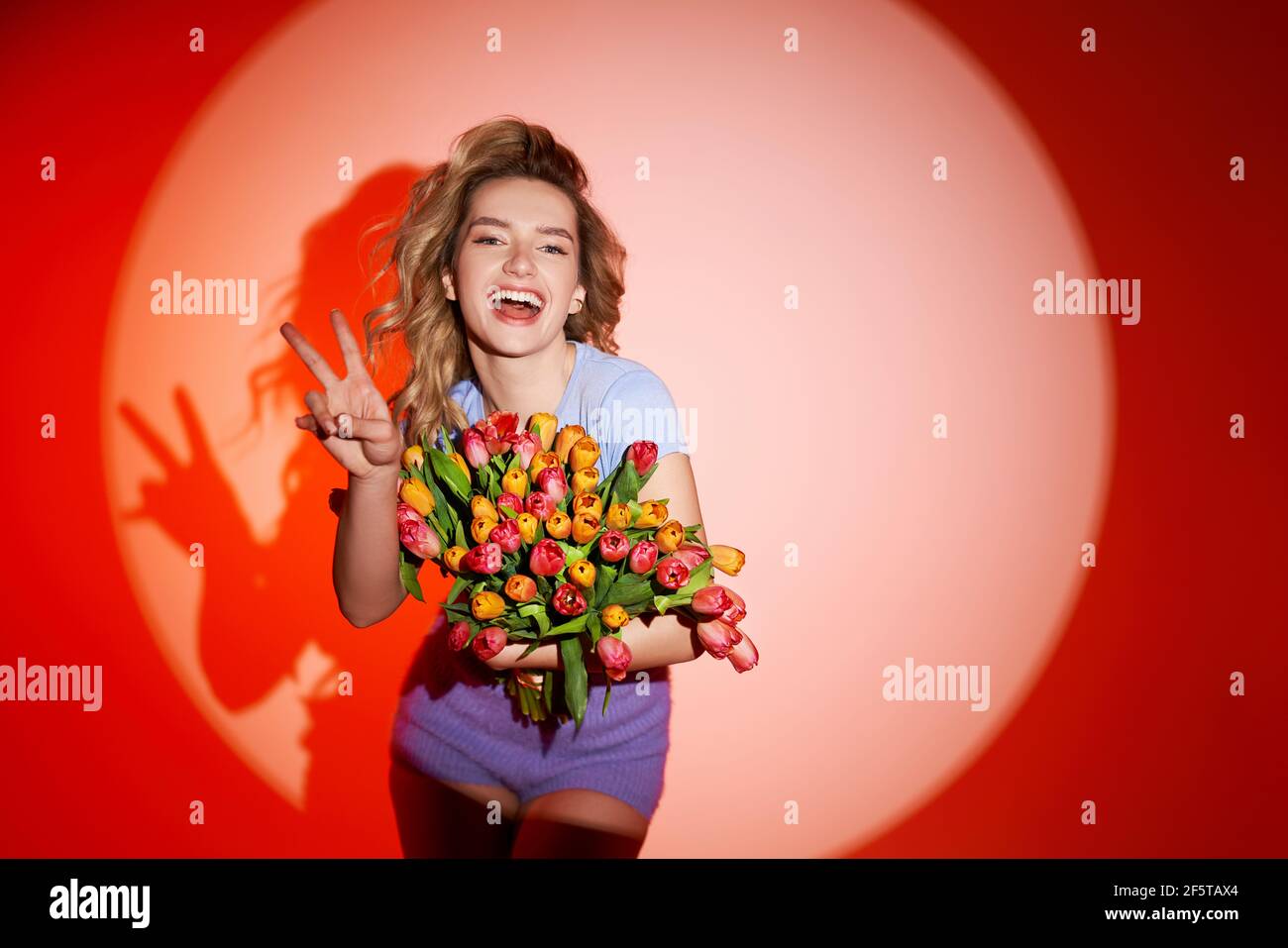 Young woman with bouquet of tulips, dancing in studio. Summerstyle Stock Photo