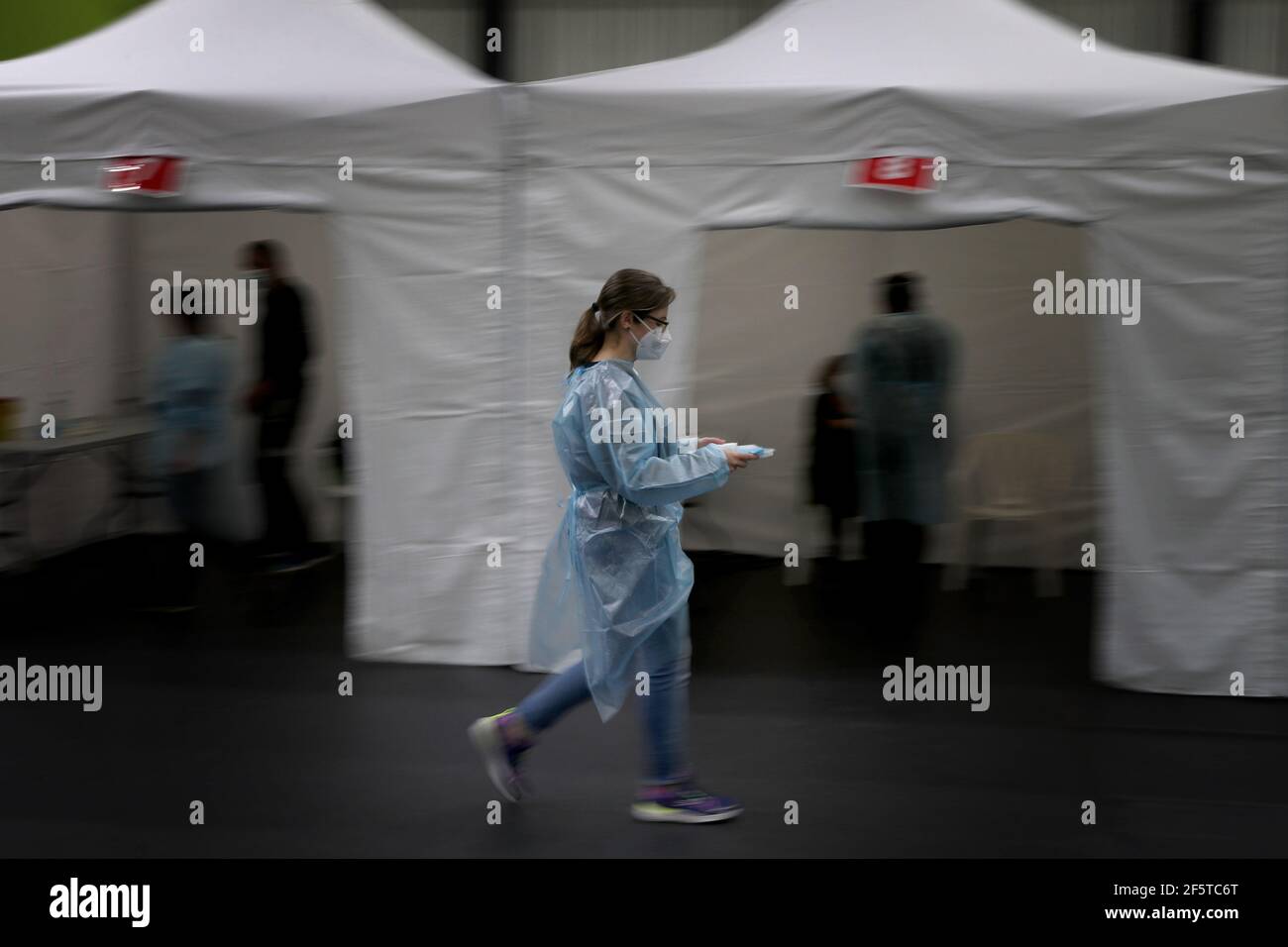 Lisbon, Portugal. 27th Mar, 2021. A medical worker holding a tray with the AstraZeneca COVID-19 vaccine walks by vaccination booths in Lisbon, Portugal, March 27, 2021. Portugal on Saturday started vaccinations of some 78,700 teachers and workers from pre-schools and schools of the first four years of the nine-year basic education. They are listed as one of the priority groups for the resumption of classes. Credit: Pedro Fiuza/Xinhua/Alamy Live News Stock Photo
