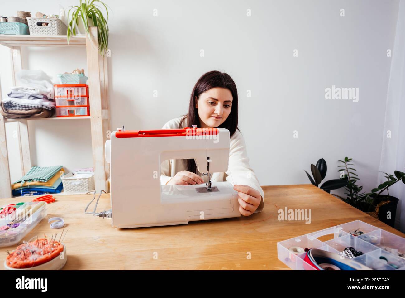 Closeup hands inserting thread into sewing machine needle Stock Photo