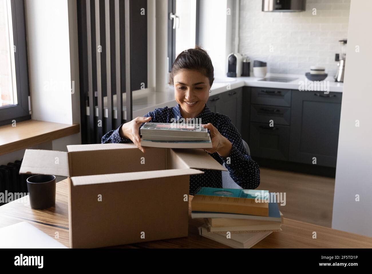 Smiling Indian young woman unpacking parcel with internet order Stock Photo