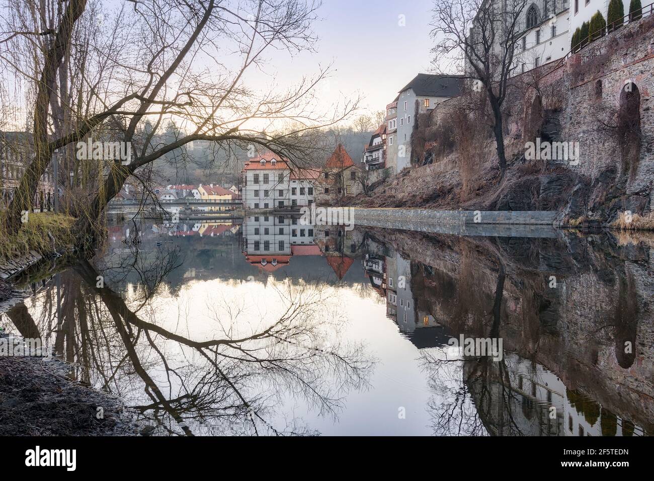 Picturesque view of aged shabby residential buildings reflecting in calm water of river Stock Photo