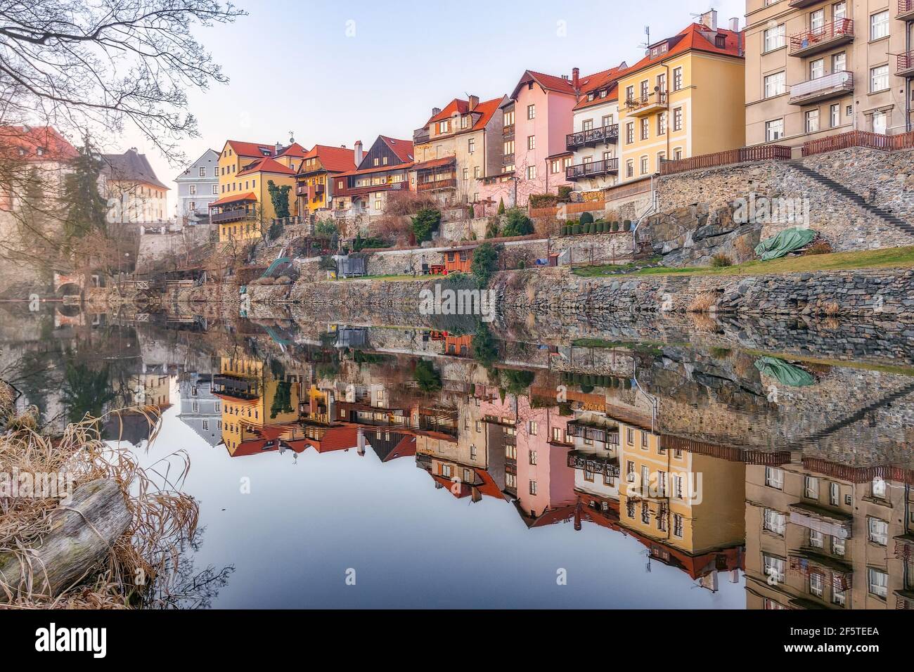 Picturesque view of aged shabby residential buildings reflecting in calm water of river Stock Photo