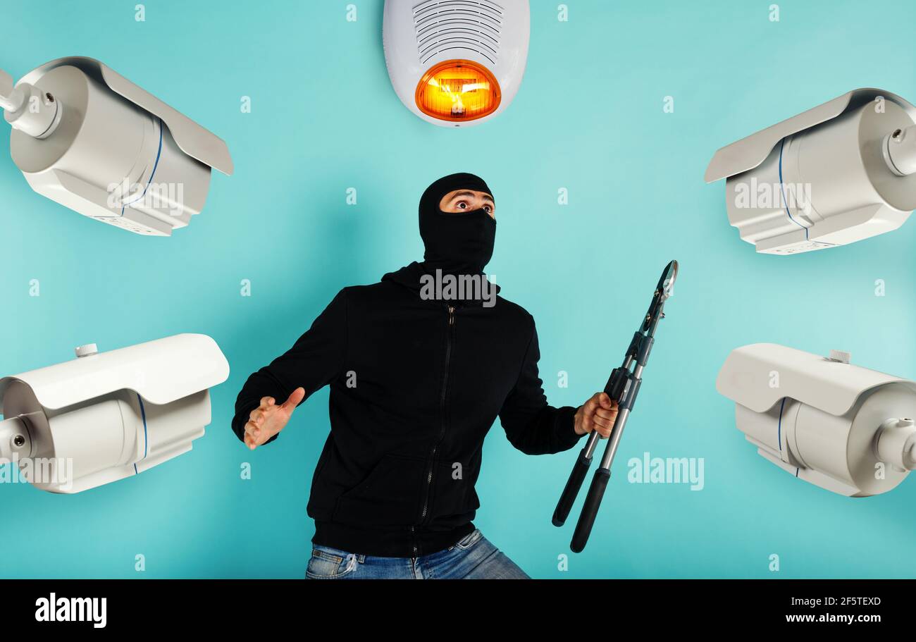 Thief with balaclava and wire cutter was spotted trying to steal in a apartment from the security alarm system. Scared expression Stock Photo