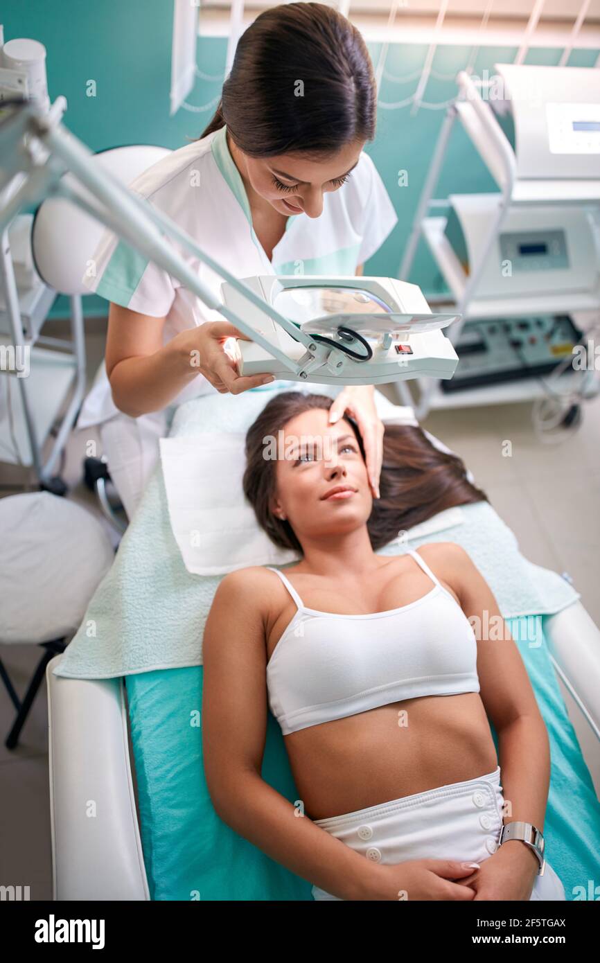 Cosmetologist  preparing woman for facial treatment by beautician at clinic Stock Photo