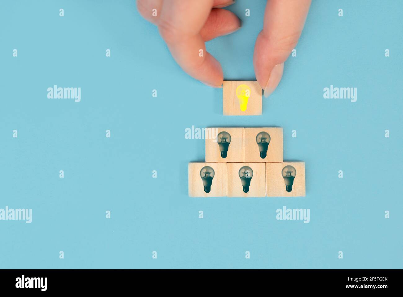Hand taking a wooden cube with the yellow light bulb symbol on pastel ...