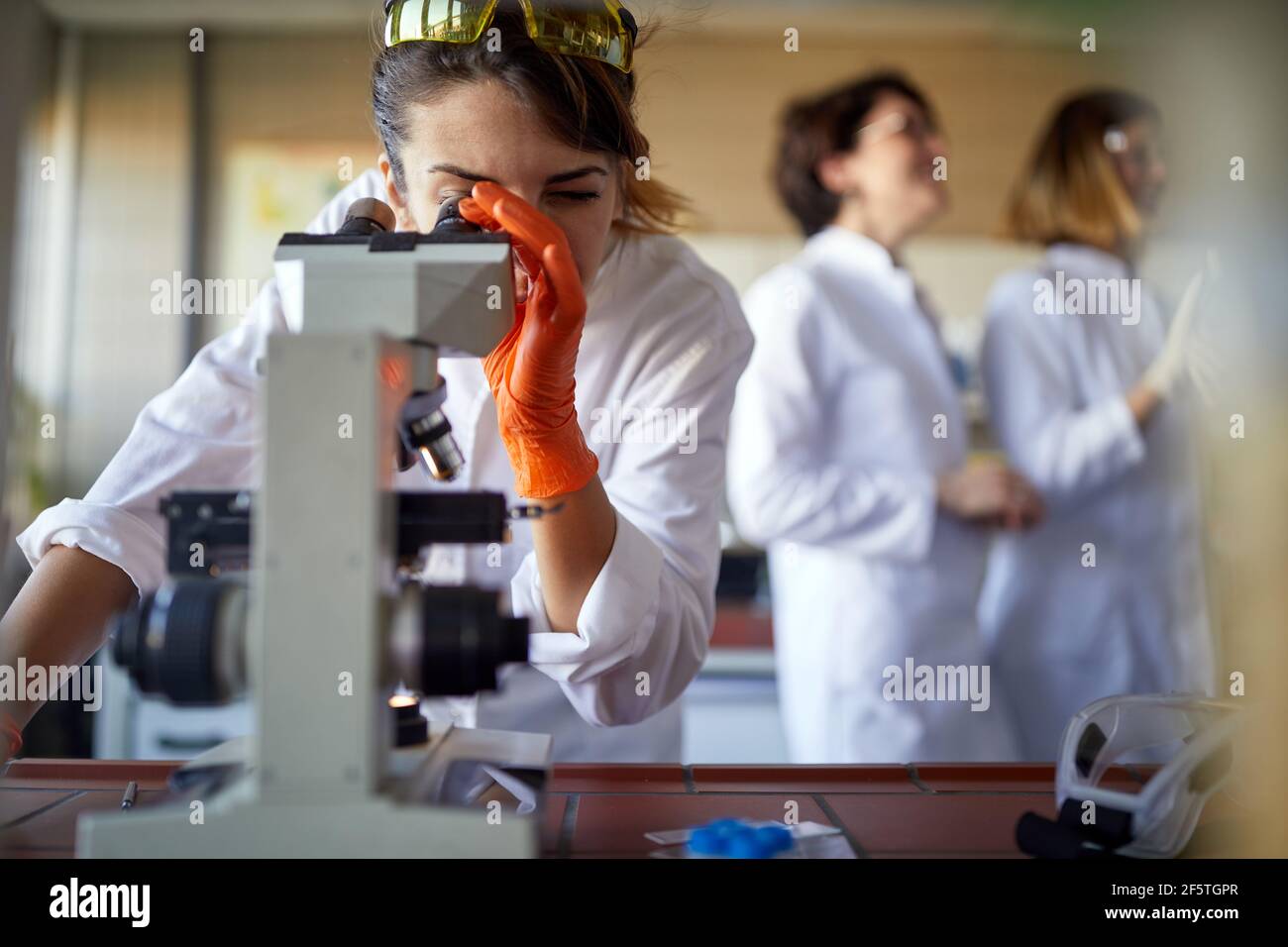 Young female student working at the microscope in the university laboratory in a relaxed atmosphere. Science, chemistry, lab, people Stock Photo