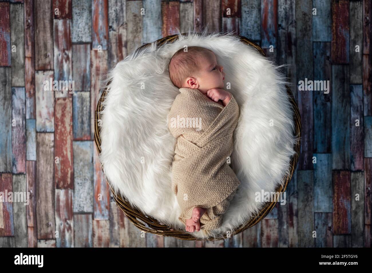 Little newborn baby sleeping in wooden basket on fluffy blanket, new