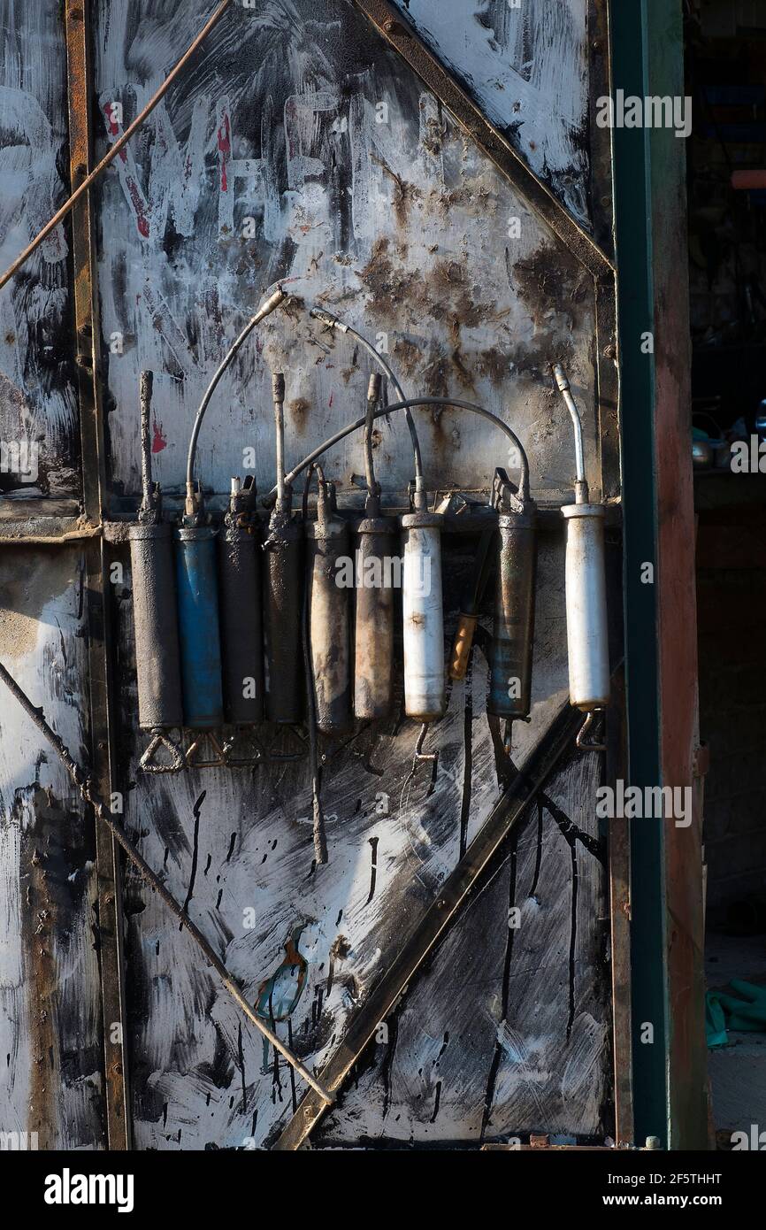 Grease guns hanging on the wall of a farm workshop used for the care and maintenance of moving parts Stock Photo
