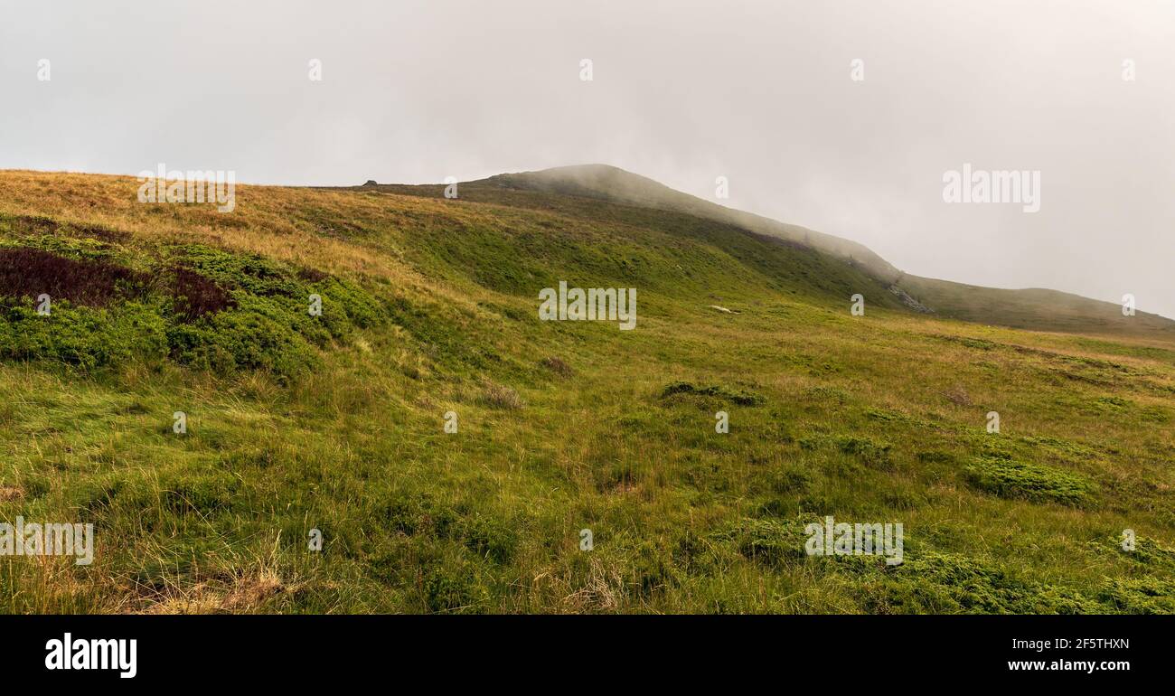 Hills covered by meadows during cloudy day in Carpathian mountains in Romania - Muntii Valcan above Straja resort Stock Photo